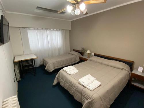 a hotel room with two beds and a table and a window at Hotel Plaza in Coronel Suárez