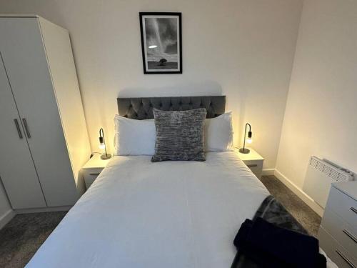 a bedroom with a large white bed with two lamps at Cosy MCR 1 Bed Apt with Balcony in Manchester