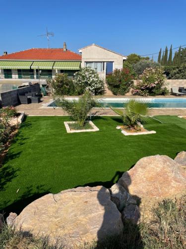 a yard with green grass and a swimming pool at les olivades in Magalas