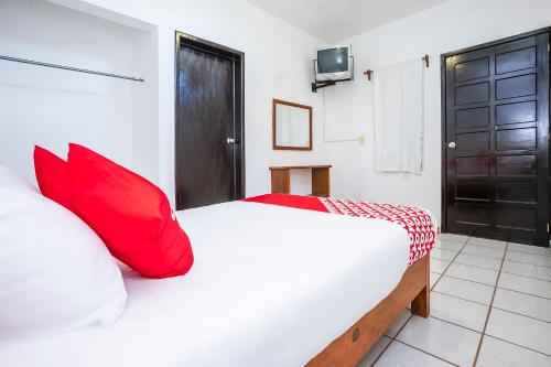 a bedroom with a white bed with red pillows at OYO Hotel Mexico in Chetumal