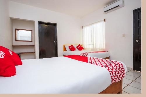 two beds in a room with red and white pillows at OYO Hotel Mexico in Chetumal