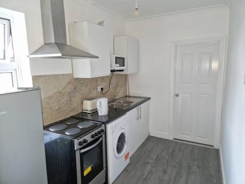 a kitchen with a stove and a washing machine at Inviting 2-Bed Apartment in Ilford in Ilford