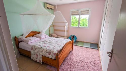 a small bedroom with a bed with a canopy at Villa Frangipanier in Case-Pilote