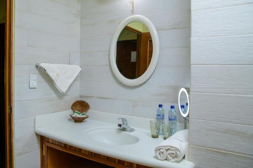 W łazience znajduje się umywalka i lustro. w obiekcie Banana Palms Hotel w mieście Rio Dulce