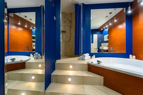 ein Badezimmer mit zwei Waschbecken, einer Badewanne und einem Spiegel in der Unterkunft 90m2 Golden Dragon Prestige Suite - Parking, Air Conditioner, Jacuzzi, Balcony, Park Nearby - by Rentujemy in Warschau