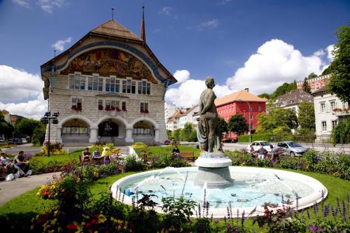 una estatua en una fuente frente a un edificio en Hôtel des Trois Rois, en Le Locle