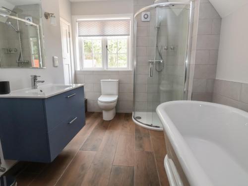 y baño con bañera, aseo y ducha. en 2 Golf Links Cottages, en Northwich