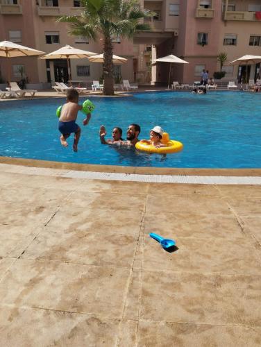 twee kinderen spelen in een zwembad in een hotel bij Résidence calme avec piscine Plage à 5min in Mohammedia