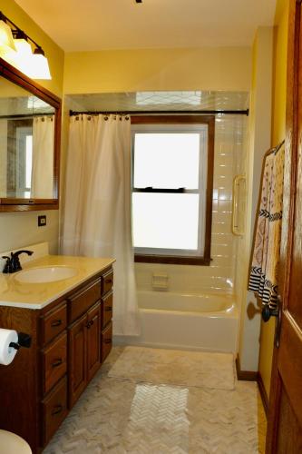 a bathroom with a sink and a tub and a window at Historic Home with Outdoor Hot Tub Near Downtown in Public Transportation Hub in Chicago