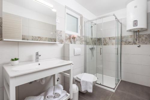 een witte badkamer met een wastafel en een douche bij Holiday Homes Oštro in Kraljevica