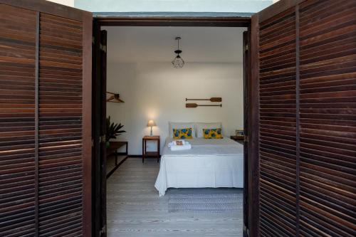 um quarto com uma cama num quarto com portas de madeira em Ilhabela Studios em Ilhabela