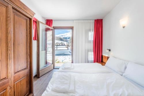 sypialnia z łóżkiem i dużym oknem w obiekcie Residence Nevegall w Livigno