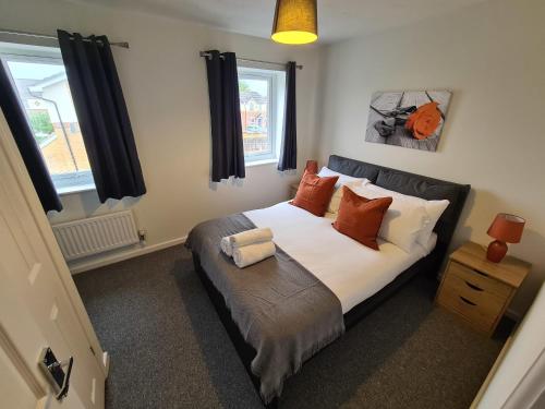 1 dormitorio con 1 cama con almohadas de color naranja en 2 Bedroom house in Bradley Stoke- Hopewell, en Bristol