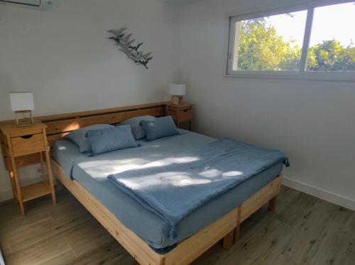 Schlafzimmer mit einem Bett mit blauer Bettwäsche und einem Fenster in der Unterkunft Laurent le Goéland, maison les pieds dans l'eau in Sète