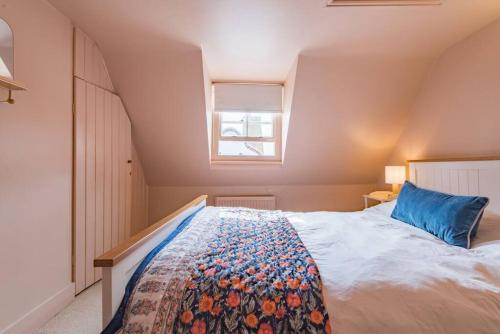 a bedroom with a bed with a blue pillow and a window at Coop's Landing - Charming seaside bolthole in Deal