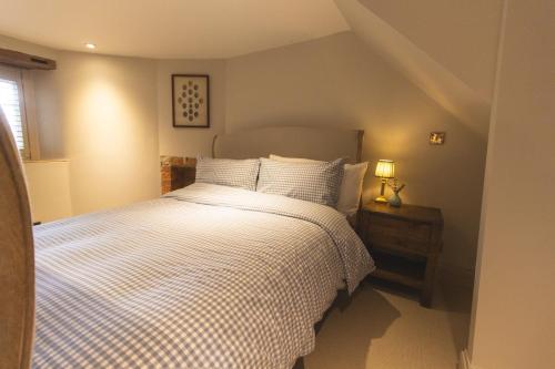 a bedroom with a bed with a checkered blanket at Cotswold Cottage- Central Witney in Witney