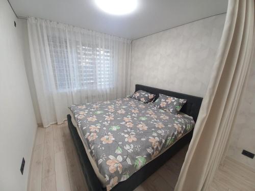 a bedroom with a bed with a floral comforter and a window at Rose Valley Center Chisinau in Chişinău