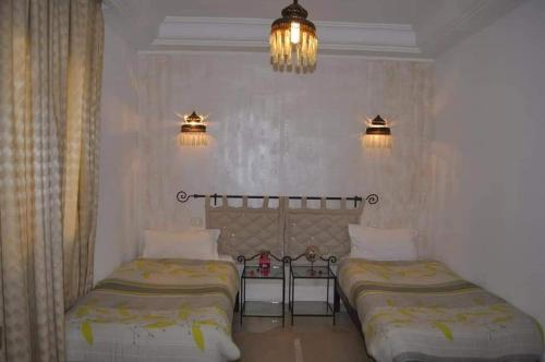 1 dormitorio con 2 camas, 2 luces y lámpara de araña en Résidence Chahd de Charme en Mezraya