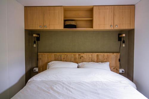 Bett mit einem Kopfteil aus Holz und Schränken darüber in der Unterkunft Het Hoefje in Sint-Annaland
