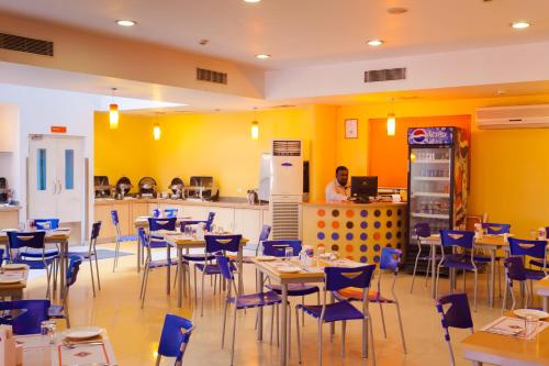 a restaurant with tables and chairs and a man in the kitchen at Ginger Vadodara in Vadodara