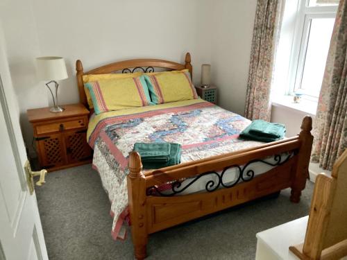 a bedroom with a wooden bed and a window at Spacious cottage, central Ballycastle. in Ballycastle