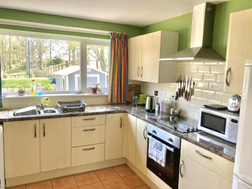 a kitchen with white cabinets and a large window at Spacious cottage, central Ballycastle. in Ballycastle