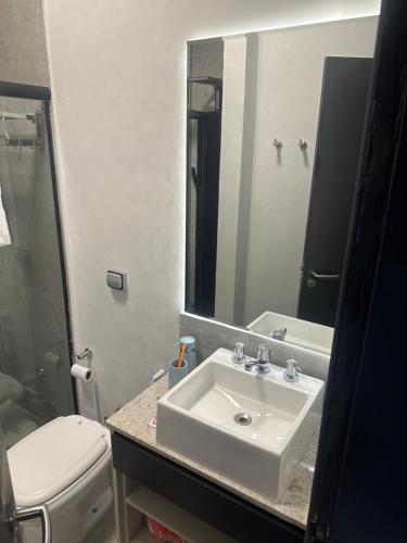 a bathroom with a sink and a toilet and a mirror at Casa térrea com acessibilidade em Juquehy com piscina climatizada e hidromassagem in Juquei