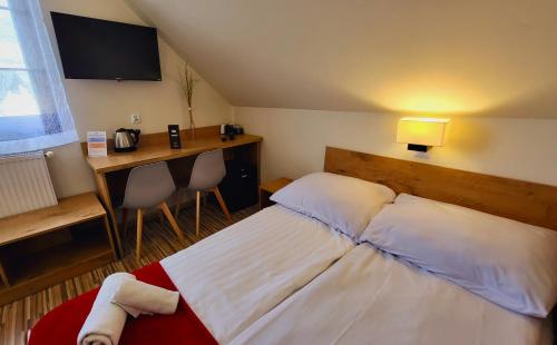 a bedroom with a bed and a desk and a television at Gościniec Konopielka in Zblewo