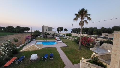 un patio trasero con piscina, sillas y una palmera en Villa Alex, en Tavronitis