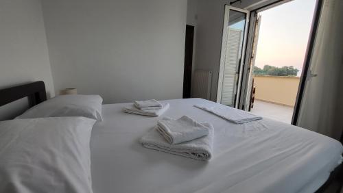 Una cama blanca con toallas encima. en Villa Alex, en Tavronitis