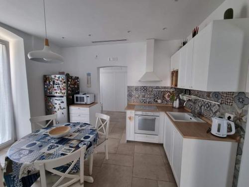 cocina con mesa y cocina con armarios blancos en Dimora San Michele, en Giovinazzo