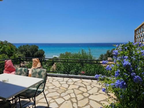 a patio with a table and chairs and the ocean at Corfu Glyfada Beach Apartment in Glyfada