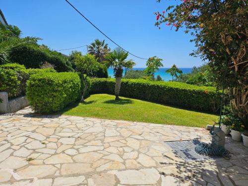 a garden with a stone walkway and bushes at Corfu Glyfada Beach Apartment in Glyfada