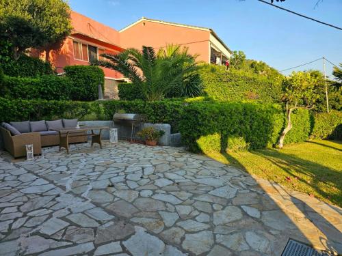 a stone patio with a bench and a hedge at Corfu Glyfada Beach Apartment in Glyfada