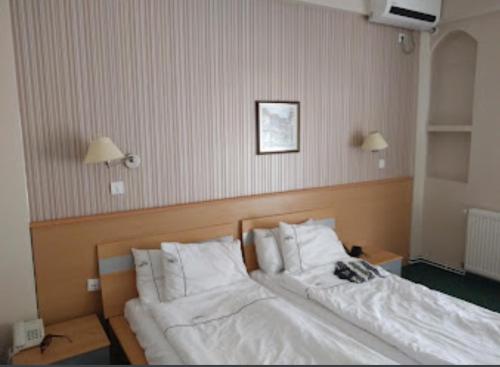 a bedroom with two beds with white sheets and pillows at Hotel Bluebell in Ohrid