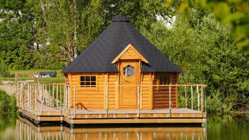 a log cabin with a black roof on the water at Les Cabanes Flottantes in Givrauval