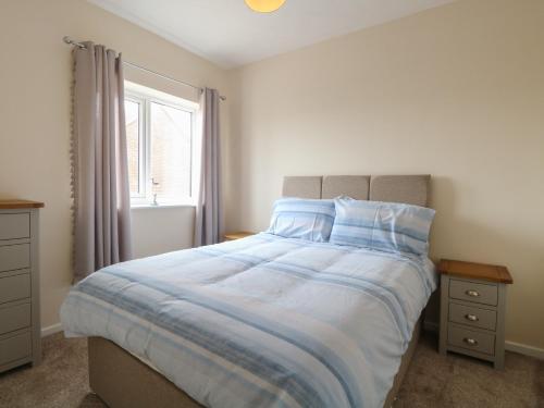 a bedroom with a bed with blue sheets and a window at The Look Out in Sea Palling