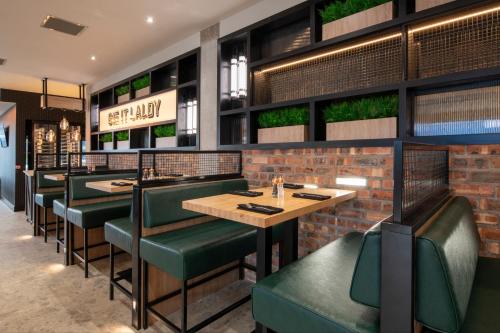 a restaurant with green seats and a brick wall at Sandman Signature Glasgow Hotel in Glasgow