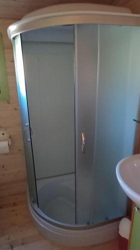 a shower with a glass door next to a sink at Roulotte de la Petite Beauronne in Les Lèches