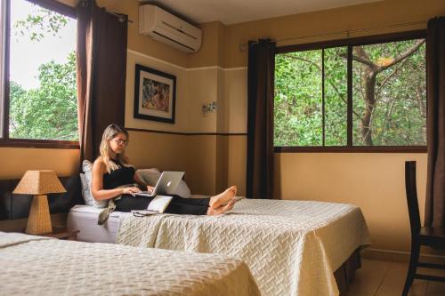 Manglar Lodge في سان كارلوس: امرأة جالسة على سرير مع جهاز كمبيوتر محمول