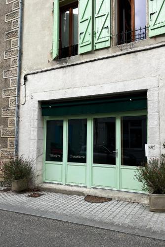 una tienda con puertas verdes al lado de un edificio en Le Petit Gîte des Lys, en Monségur