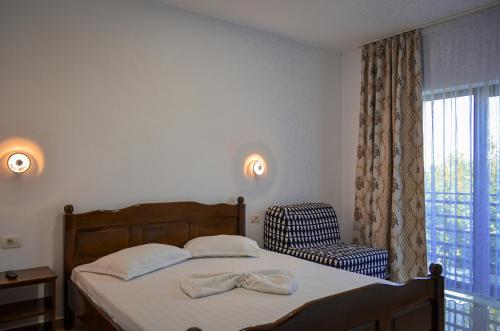a bedroom with a bed and a chair and a window at ROMSIL GUESTHOUSE in Costinesti