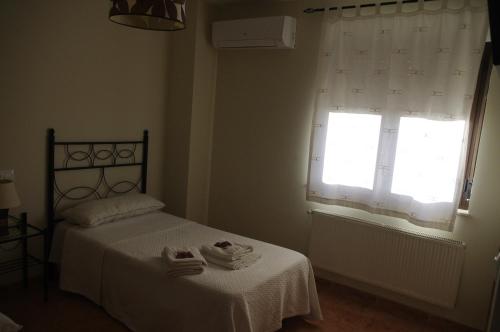 a bedroom with a bed and a window with towels on it at Hotel la Hoja*** in Aldeadávila de la Ribera