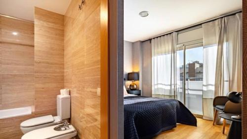 a bedroom with a bed and a bathroom with a window at HOSTAL BEDMATES in Barcelona
