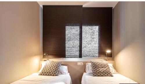 a bedroom with two beds and a window with blinds at HOSTAL BEDMATES in Barcelona