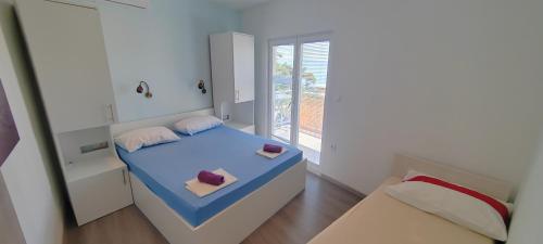a small bedroom with a blue bed and a window at Apartmani ANDRIJA in Živogošće