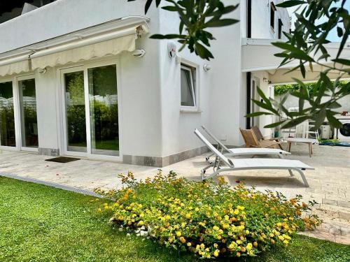 a white house with a patio with chairs and flowers at CASA MILA in Marina di Cerveteri