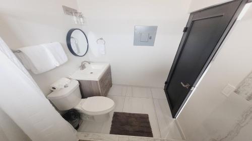 a white bathroom with a toilet and a sink at New Town Condo Casamar 4 near the beach in Puerto Peñasco