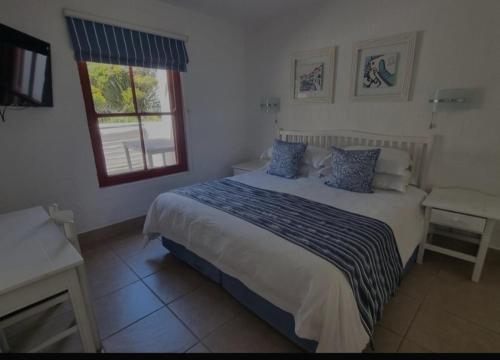 a bedroom with a large bed with a window at Kaliva 394, Club Mykonos in Langebaan