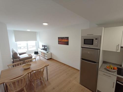 a kitchen and living room with a table and a microwave at Duerming Ría de Viveiro in Viveiro